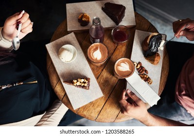 High angle of a diverse group of young friends sitting together around a cafe table enjoying an assortment of desserts and coffee - Powered by Shutterstock