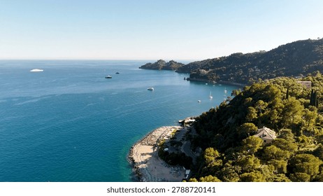 High angle drone shot captures the turquoise Mediterranean sea and lush green coastal hillsides.