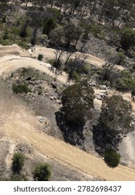 High angle drone shot of empty dirt mountain bike trails through dry Australian bushland.