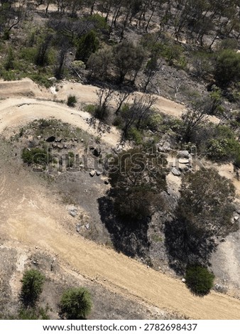High angle drone shot of empty dirt mountain bike trails through dry Australian bushland.