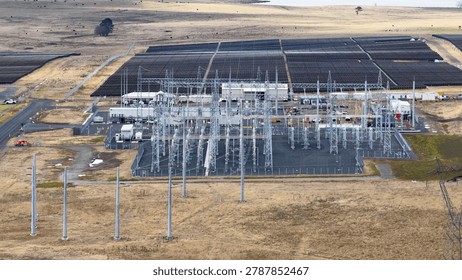 High angle drone shot of a large solar panel array and electrical power substation.