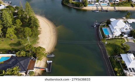 High angle drone shot of upscale riverside properties with private pools, docks, and lush landscaping.