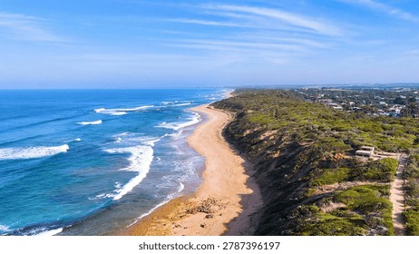 High angle drone shot of waves crashing on a sandy Australian beach.
