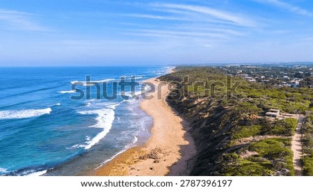 High angle drone shot of waves crashing on a sandy Australian beach.