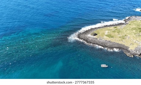 High angle drone view of turquoise ocean water and volcanic rock formations at Fingal Head.