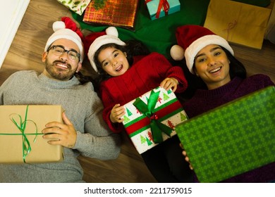 High Angle Of An Excited Family With A Kid Opening Presents Under The Christmas Tree During The Holidays