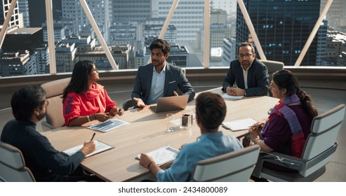 High Angle Footage of a Diverse Team of Professional South Asian Businesspeople Meeting in an Office Conference Room. Creative Team Sitting Behind a Table, Discussing Social Media Marketing Strategy - Powered by Shutterstock