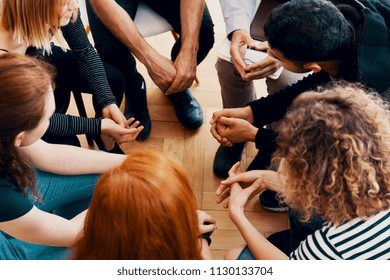 High angle of a group of teenagers sitting in a circle during group therapy for bullying victims