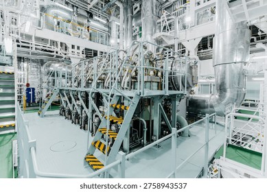 High angle interior view of a massive marine diesel engine inside a ship engine room with complex industrial piping
