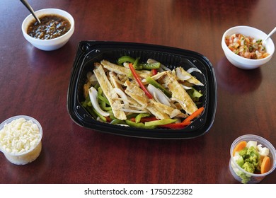 A High Angle Of Mexican Fajitas With Sliced Peppers In A Plastic Container Accompanied Rice, Salsa And Veggies