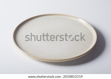 High angle of minimalist style round plate with low rim placed on gray background