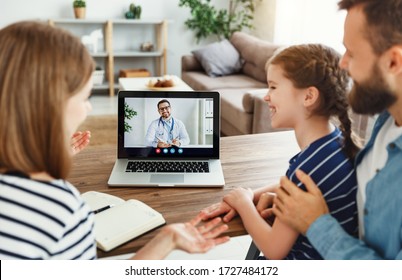 High Angle Of Modern Parents And Cheerful Daughter Sitting At Table And Speaking With Online Doctor At Home
