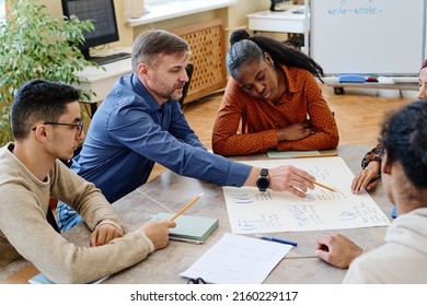 High angle of modern teacher and his immigrant students working on educational English language poster together in group - Shutterstock ID 2160229117
