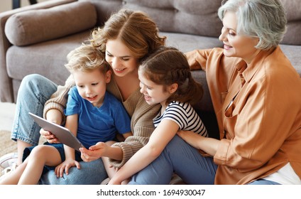 High angle of mother and grandmother sitting on floor near sofa and browsing tablet with kids in cozy living room at home
 - Powered by Shutterstock