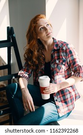 High angle on red haired woman with cup of coffee at home during renovation