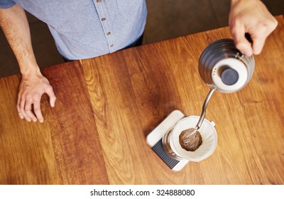 High Angle Overhead Shot Of A Man Carefully Pouring Hot Water Into The Filter Of A One-cup Coffee Filter Filled With A Measure Of A Freshly Ground Coffee