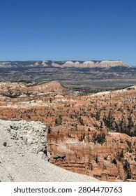 High angle panoramic view of Bryce Canyon National Park with white sandstone formations in the foreground and a vast canyon valley under a blue sky, Utah, USA. Copy space