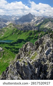 High angle panoramic view of the rugged alpine peaks and lush green mountains surrounding Schrecksee lake in the Allgau Alps