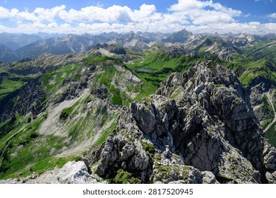 High angle panoramic view of the rugged alpine peaks and lush green mountains surrounding Schrecksee lake in the Allgau Alps