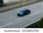 high angle photo of a blue car driving on a highway