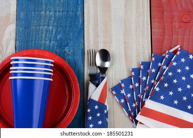 High Angle Photo Of A Fourth Of July Picnic Table Setting. The Red White And Blue Items Are On A Wood Table Painted For The Holiday.