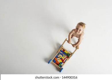 High Angle Portrait Of Baby Pushing Cart With Building Blocks On White Background