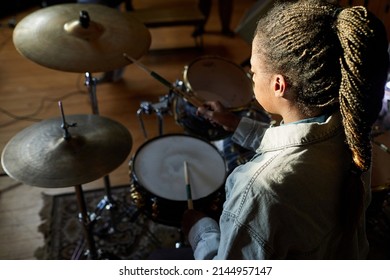 High Angle Portrait Of Black Young Woman Playing Drums In Dark With Light Accent, Copy Space