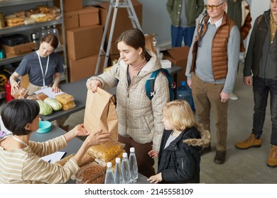 High Angle Portrait Of Caucasian Young Woman With Child Receiving Food Donations And Help In Volunteer Center For Refugees