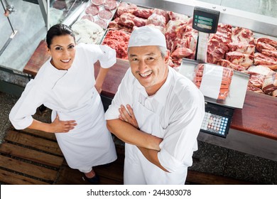 High angle portrait of confident male and female butchers standing at butchery counter - Powered by Shutterstock