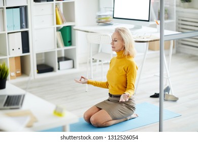 High angle portrait of contemporary mature businesswoman meditating in office, copy space - Powered by Shutterstock