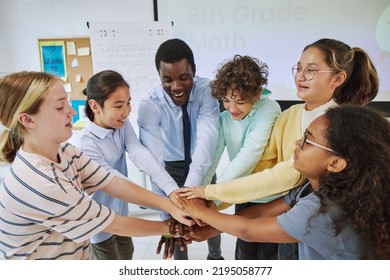 High Angle Portrait Of Diverse Schoolchildren Huddling In Team Exercise In Classroom And Stacking Hands