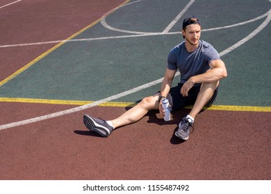 High angle portrait of handsome young man resting sitting on floor in outdoor basketball court, copy space - Powered by Shutterstock