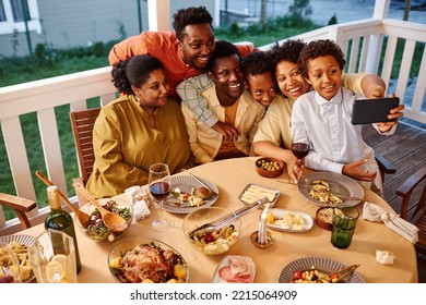 High angle portrait of happy African American family taking selfie photo at house terrace in evening - Powered by Shutterstock