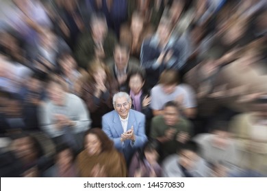 High angle portrait of senior man with crowd applauding