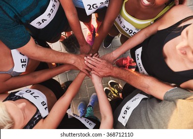 High Angle Portrait Of A Sports Team Standing In A Circle With Their Hands Stacked. Team Of Runners With Hands Together After Competition.