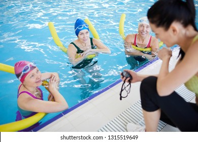 High angle portrait of three mature women doing aqua aerobics in swimming pool with female instructor, copy space - Powered by Shutterstock