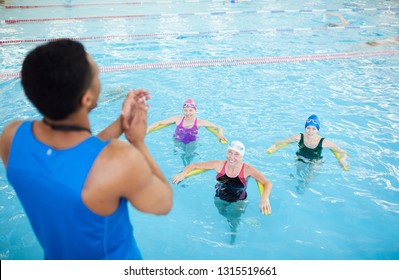 High angle portrait of three mature women doing aqua aerobics in swimming pool with fitness instructor, copy space - Powered by Shutterstock