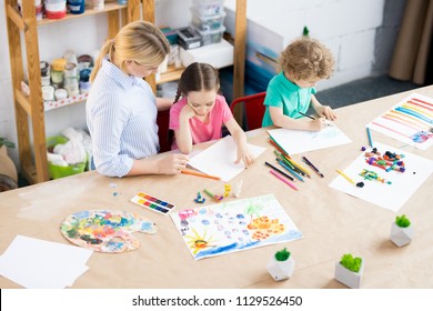 High angle portrait of two children enjoying art and craft lesson with young teacher in development school, copy space - Shutterstock ID 1129526450