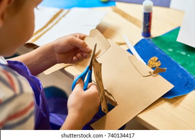 High angle portrait of unrecognizable little boy cutting paper in arts and crafts class of pre-school making handmade gift - Powered by Shutterstock