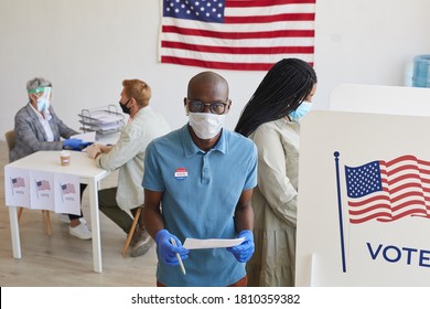 High Angle Portrait Of Young African-American Voter Wearing Mask Standing By Booth And Looking At Camera On Post-pandemic Election Day, Copy Space