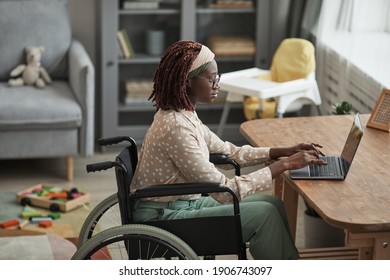 High Angle Portrait Of Young African-American Woman Using Wheelchair While Working From Home With Childrens Toys In Background, Copy Space