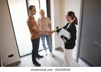 High Angle Portrait Of Young Couple Shaking Hands With Real Estate Agent During Apartment Tour, Copy Space