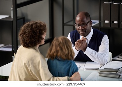 High angle portrait of young mother with child talking to caring black social worker in office - Shutterstock ID 2237954409