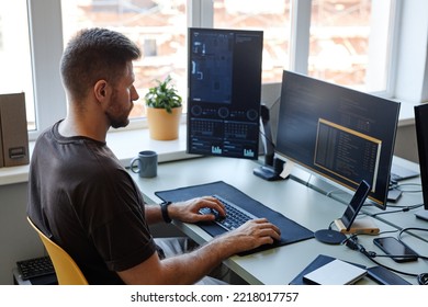 High Angle Portrait Of Young Software Engineer Writing Code At Workplace With Multiple Computer Screens