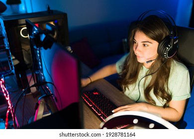 High Angle Of A Pretty Woman Wearing Headphones And Winning A Match On An Online Video Game. Female Gamer Playing In A Gaming PC With Neon Led Lights