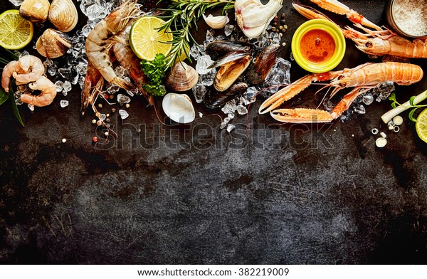 High Angle Seafood Cuisine\
Background Image with Fresh Shellfish - Shrimp, Langostino, Mussels\
and Clams - and Ingredients on Dark Background with Copy\
Space