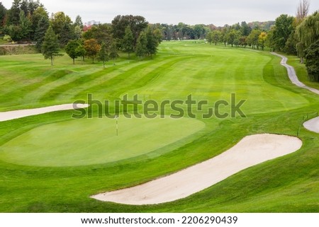 High angle selective focus view of golf course with birds and people in soft focus background seen during a cloudy morning, 