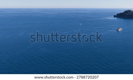 High angle shot of boats navigating calm blue waters along the Italian Riviera coastline.