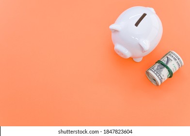A high angle shot of dollar bills and a piggy bank on an orange surface - Shutterstock ID 1847823604