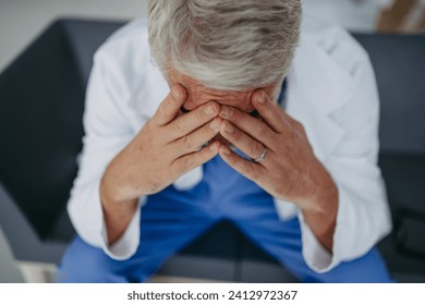 High angle shot of frustrated, exhausted doctor sitting in hospital corridor. Concept of burnout syndrome among doctors. - Powered by Shutterstock